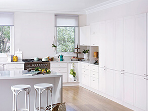 clean_white_kitchen_timber_floorboards_colourful_appliances_white_stools_grey stovetop_green_trees